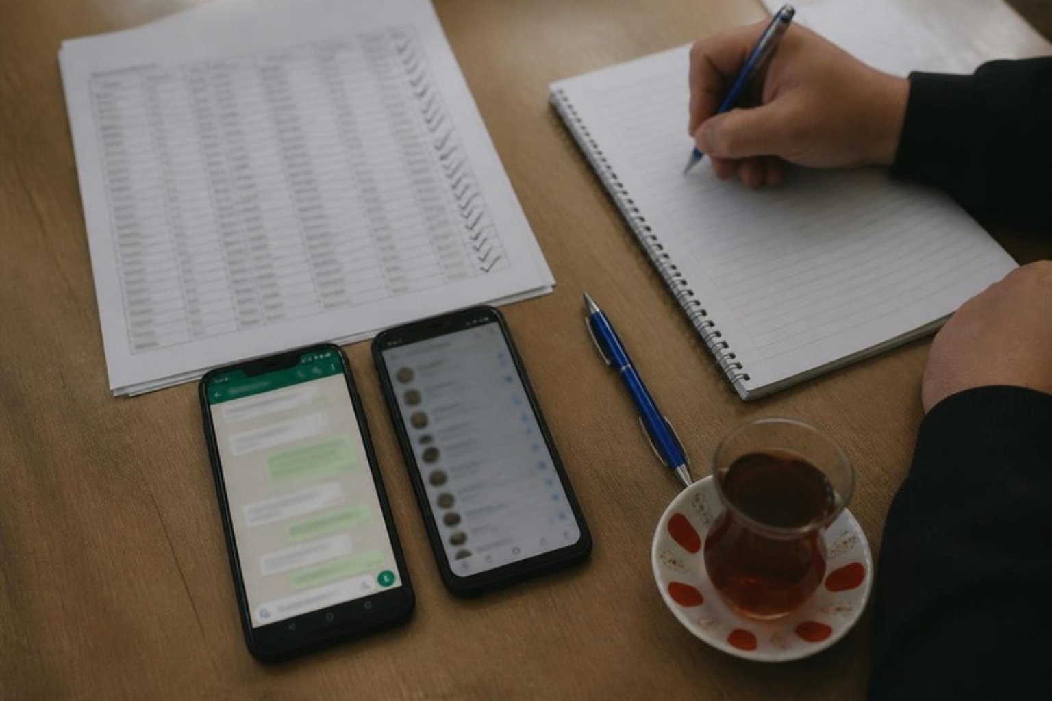 Two phones on a table, a marked customer list and a glass of tea